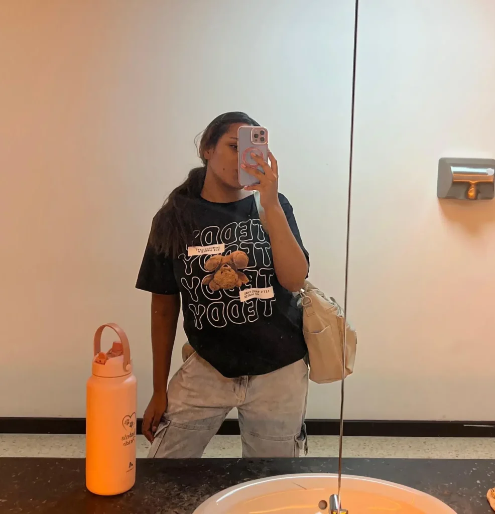 Persona en el espejo de un baño universitario.